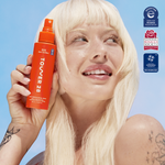 Woman holding an orange bottle of Tovaer 28 against a blue background with certification logos. [Shared]