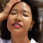 A model wearing the Tower 28 Beauty ShineOn Lip Jelly in the shade XOXO on her lips. [XOXO]